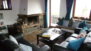 Una sala de estar con chimenea, sofás de cuero, una mesa de centro y una estantería.