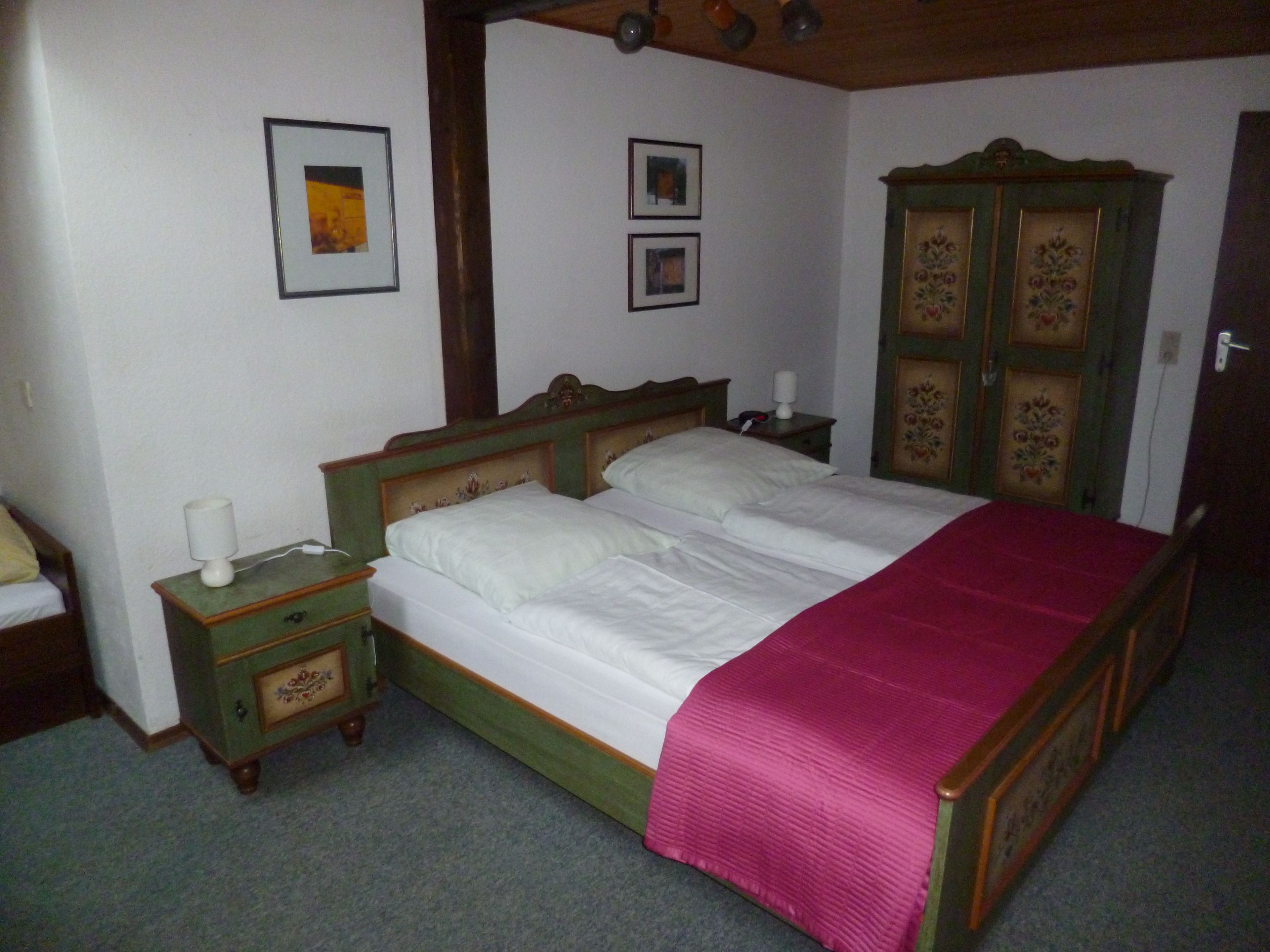 Een slaapkamer met een bed, een nachtkastje, een dressoir en twee ingelijste foto's aan de muur.