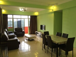 A living room with a sofa, chairs, a dining table, and a TV. - Cameron Pasar Malam Apartment at Crown Imperial Court (Brinchang)