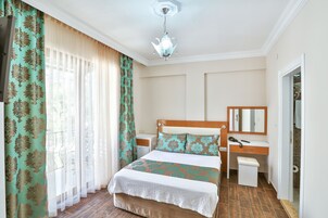 Un dormitorio ordenado con cama, mesita de noche y espejo.