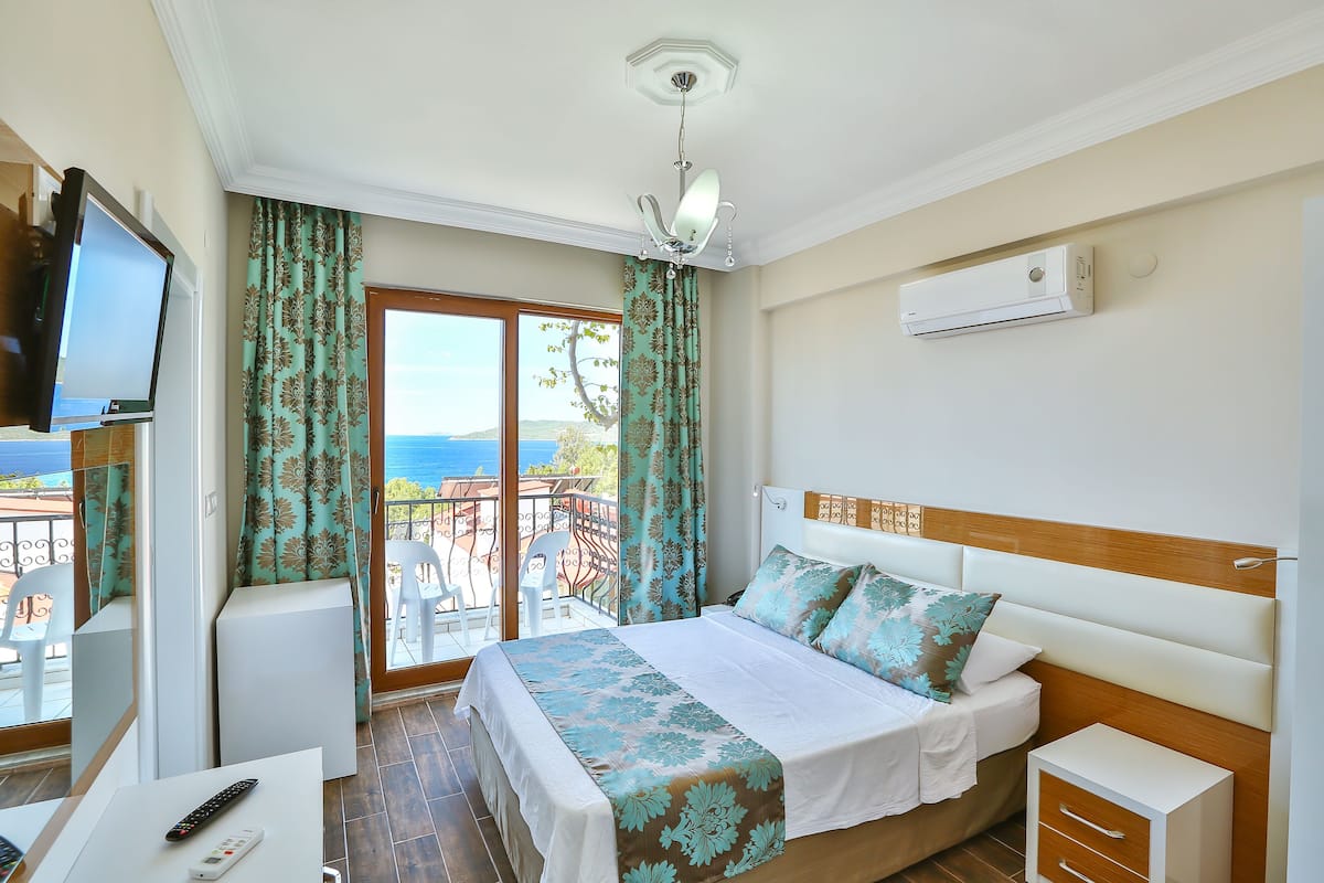 Une chambre d’hôtel avec un lit, une table de chevet, une télévision et un balcon avec des rideaux.