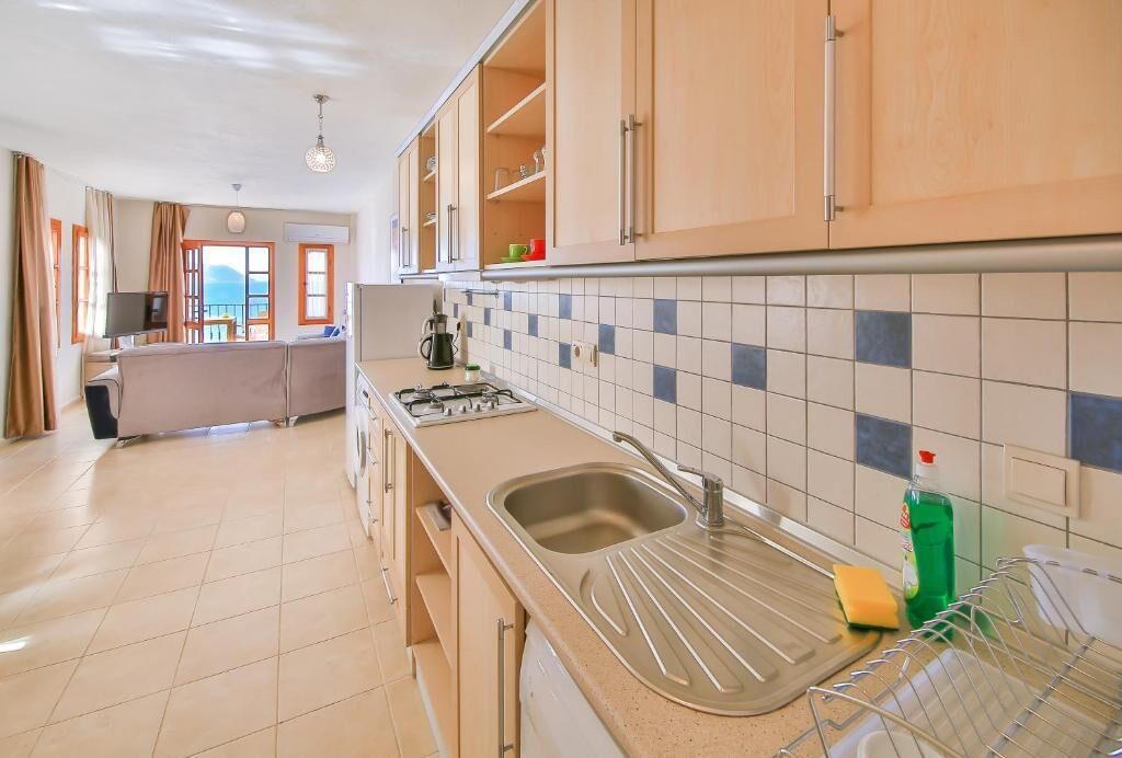 Una cocina moderna con gabinetes color crema, salpicadero de azulejos, un lavamanos y una estufa.