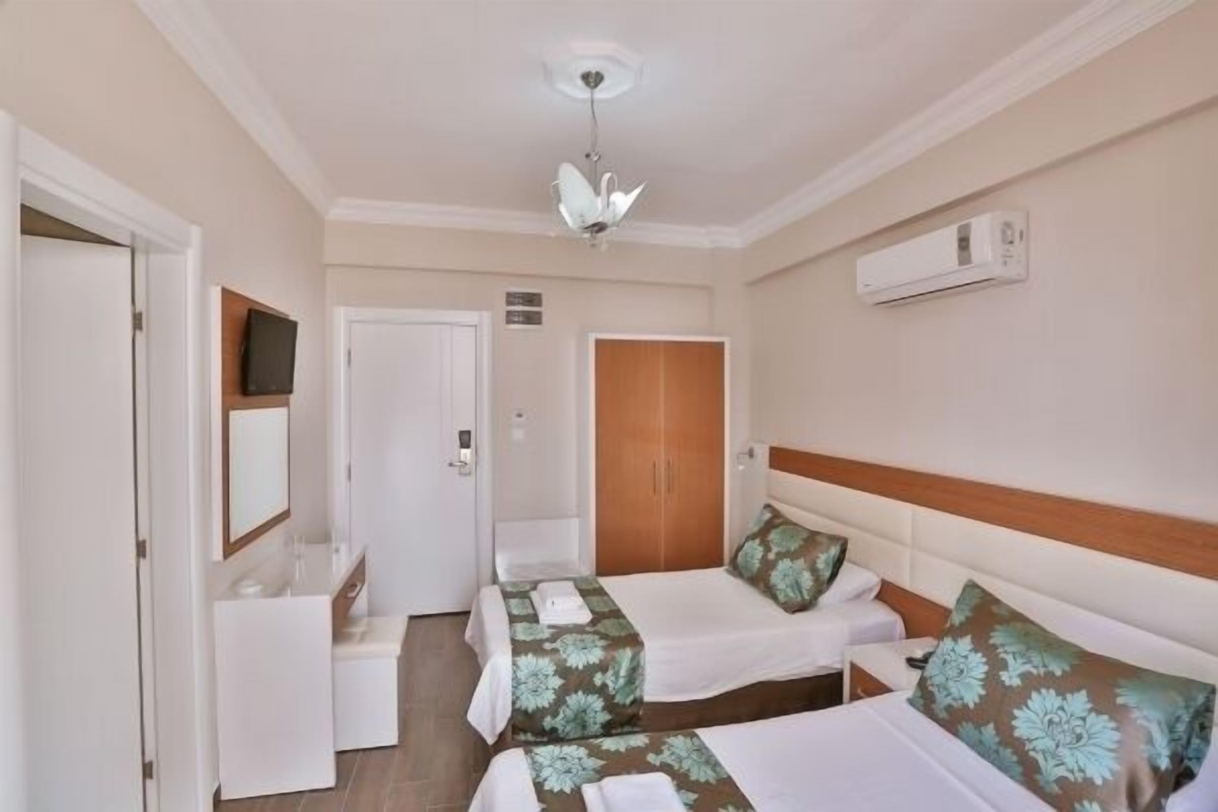 Een hotelkamer met twee bedden, een badkamer, een televisie en airconditioning.