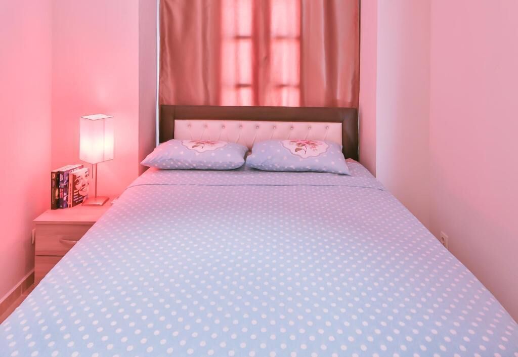 A bedroom with a bed, a nightstand, a lamp, and a window with curtains.