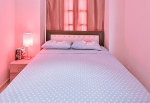 A bedroom with a bed, a nightstand, a lamp, and a window with curtains.