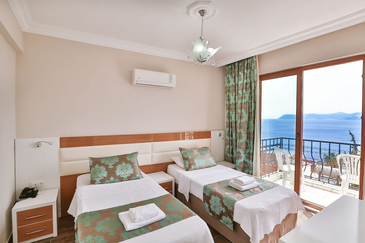 Une chambre d’hôtel avec deux lits, un balcon avec vue et un ventilateur de plafond.