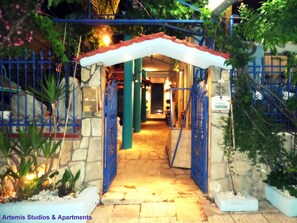 A gated entrance to a property with stone walls and a tiled pathway leading to a door. - Artemis Studios & Apartments (Nea Propontida)