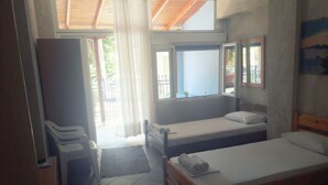 Un dormitorio con dos camas individuales, un armario de madera, un escritorio y una ventana con vistas al exterior.