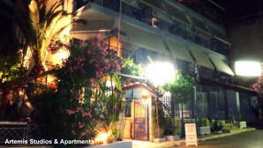 Un edificio de varios pisos con balcones, una entrada con reja y un cartel que indica habitaciones para alquilar.