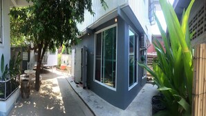 A modern building with large windows, a covered patio area, and surrounding greenery. - Nicha Homestay Huahin (Hua Hin)