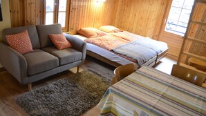 A cozy room with a sofa, a bed, a dining table, and a rug. - Studios du Valsorey (Bourg-Saint-Pierre)