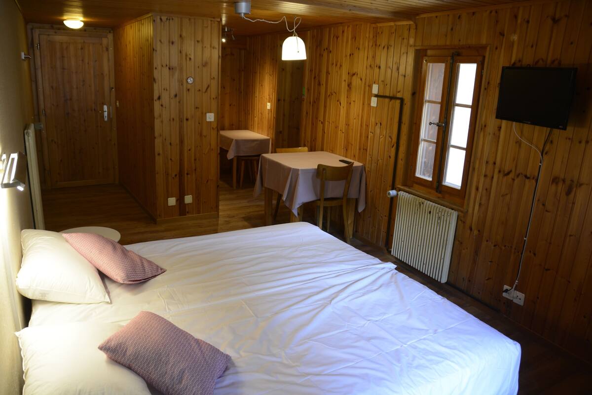 A wooden room with a bed, a table, and a chair.