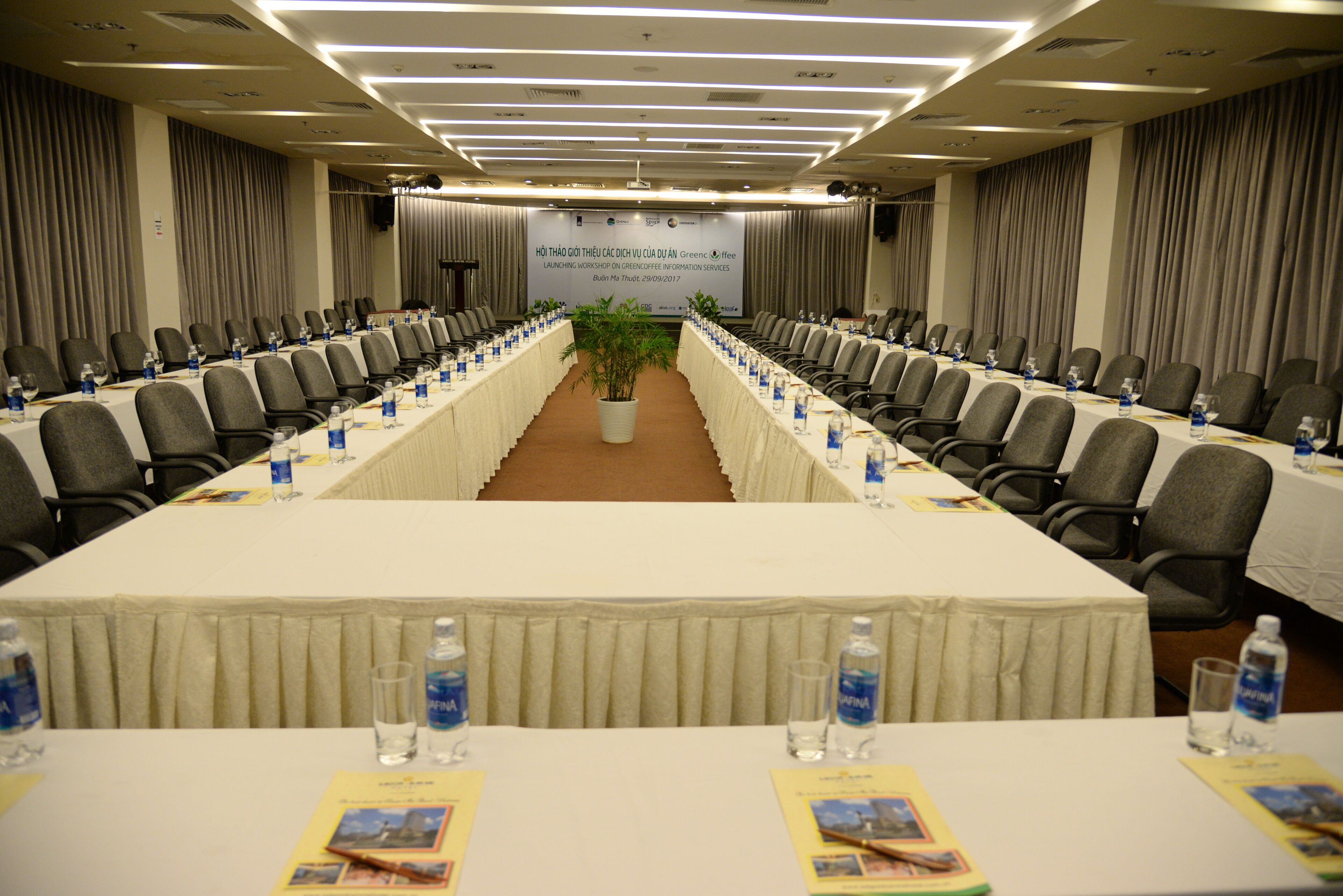 A conference room with a long table, chairs, water bottles, and informational brochures.