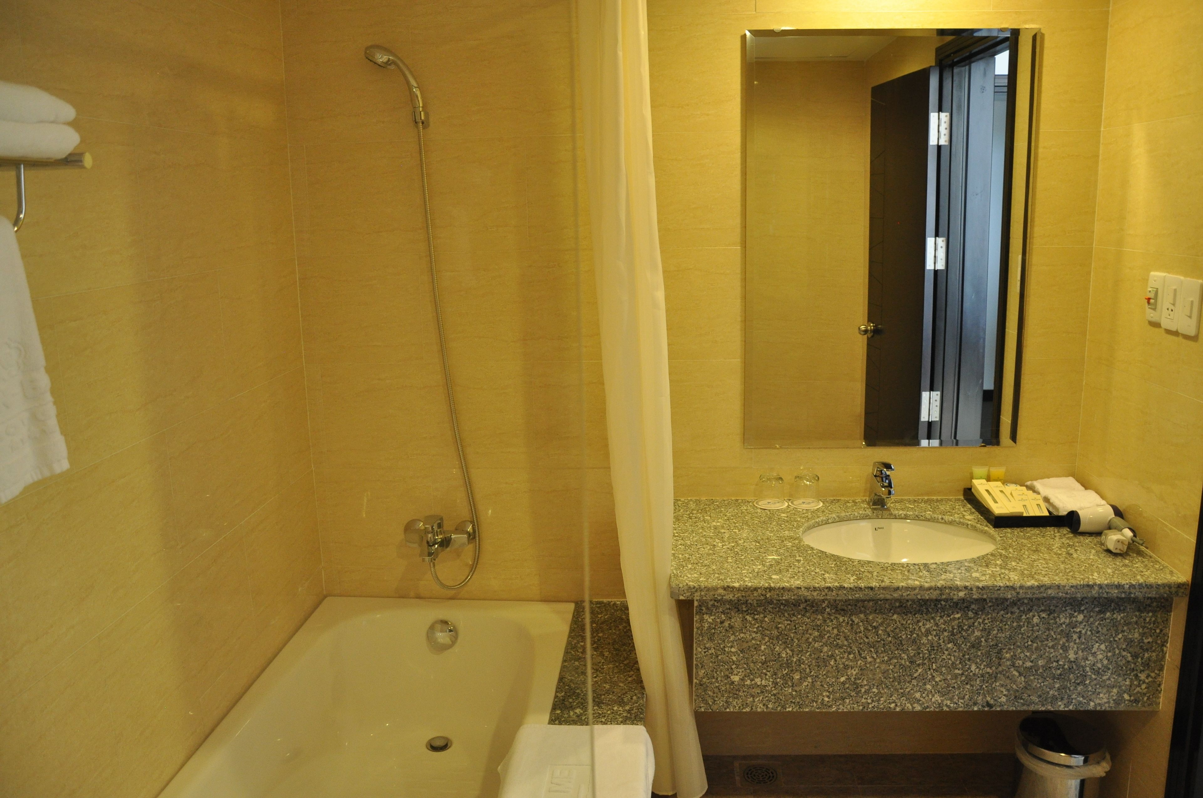 A bathroom with a bathtub, shower, sink, and mirror.