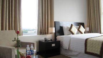 Ein Hotelzimmer mit Bett, Nachttisch, Lampe und Blick ins Freie.