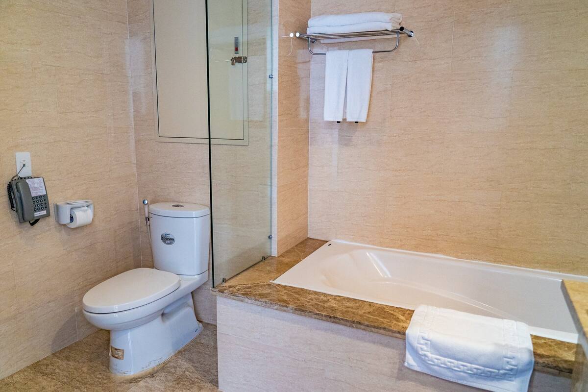Une salle de bain comprenant des toilettes, un espace de douche vitré et une baignoire avec une serviette à proximité.