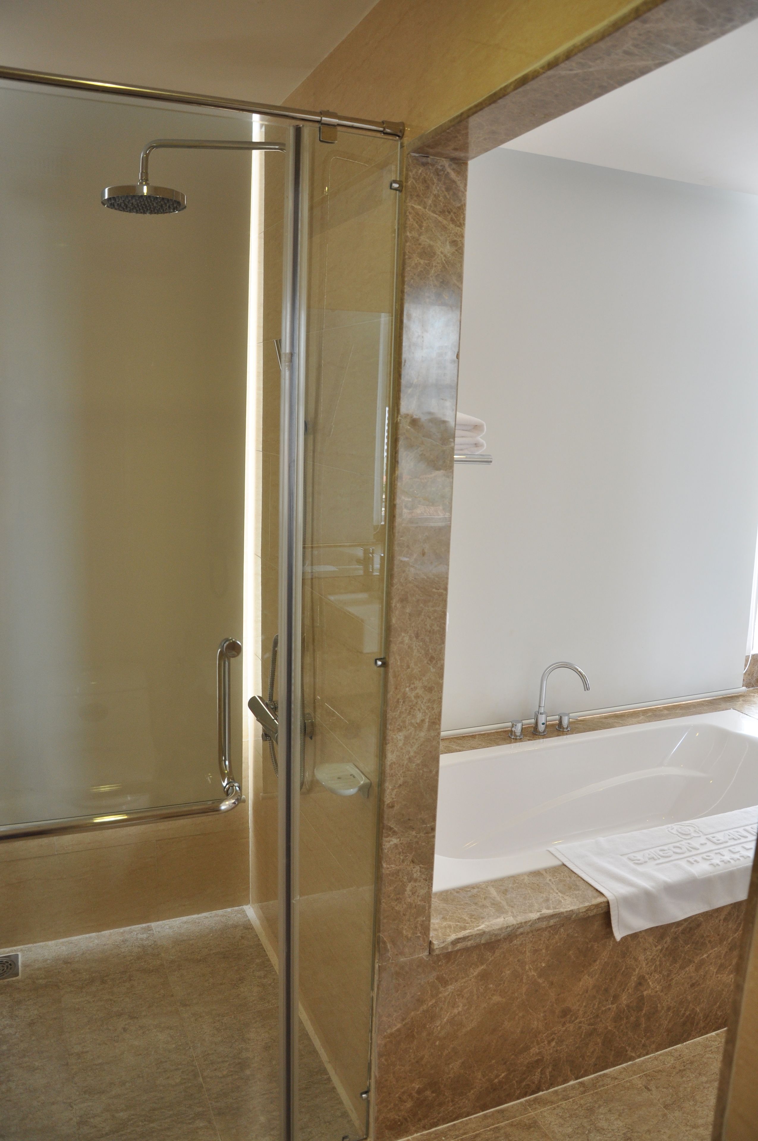 A modern bathroom with a glass-enclosed shower, a large mirror, and a bathtub.