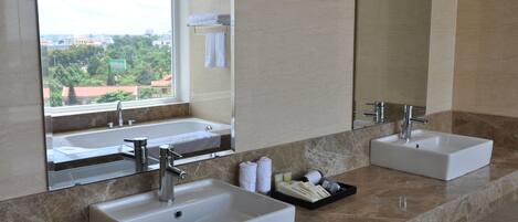 A modern bathroom with two sinks, a large mirror, and a view of a cityscape through a window.
