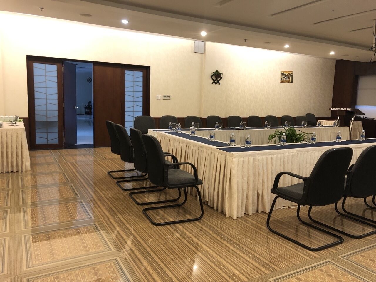 Une salle de conférence avec une longue table, des chaises noires et un sol recouvert de moquette.