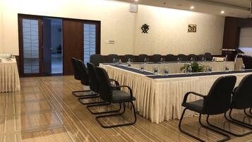 Une salle de conférence avec une longue table, des chaises noires et un sol recouvert de moquette.