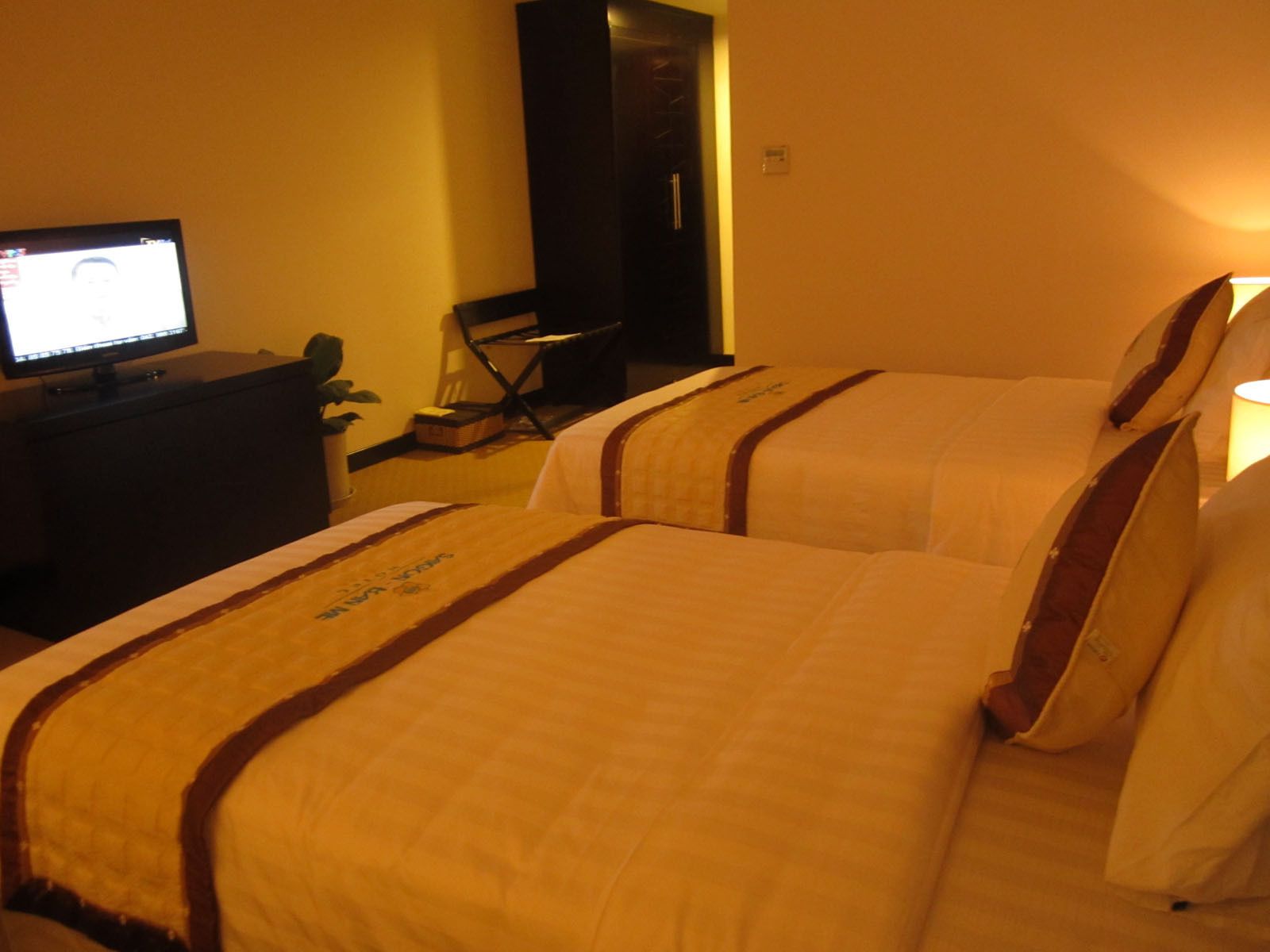 A hotel room with two beds, a desk with a computer, a chair, and a television.