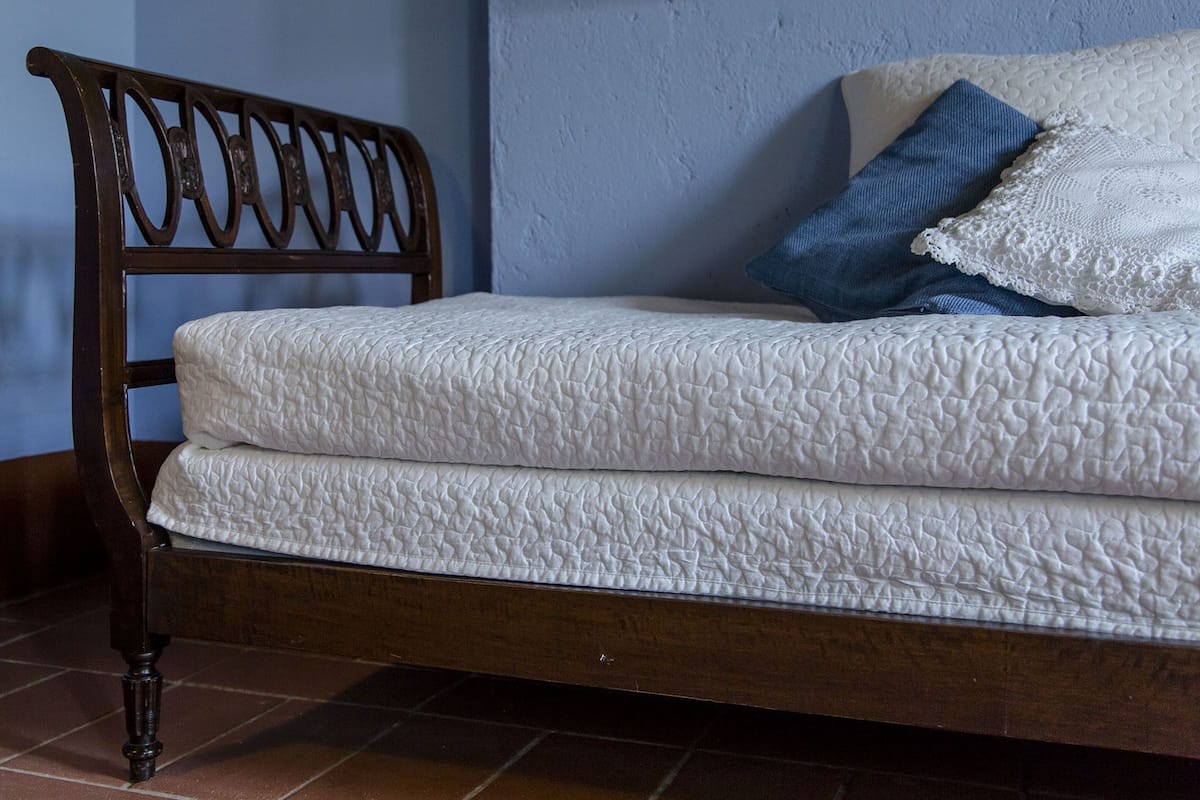 A wooden bed with a quilted mattress and a headboard with a decorative design.