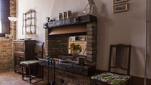 A rustic kitchen with a stone fireplace, wooden furniture, and a flower vase. - La Locanda di Sant'Anna (Truccazzano)