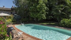 A rectangular swimming pool with clear water, surrounded by lush greenery and a brick border. - La Locanda di Sant'Anna (Truccazzano)