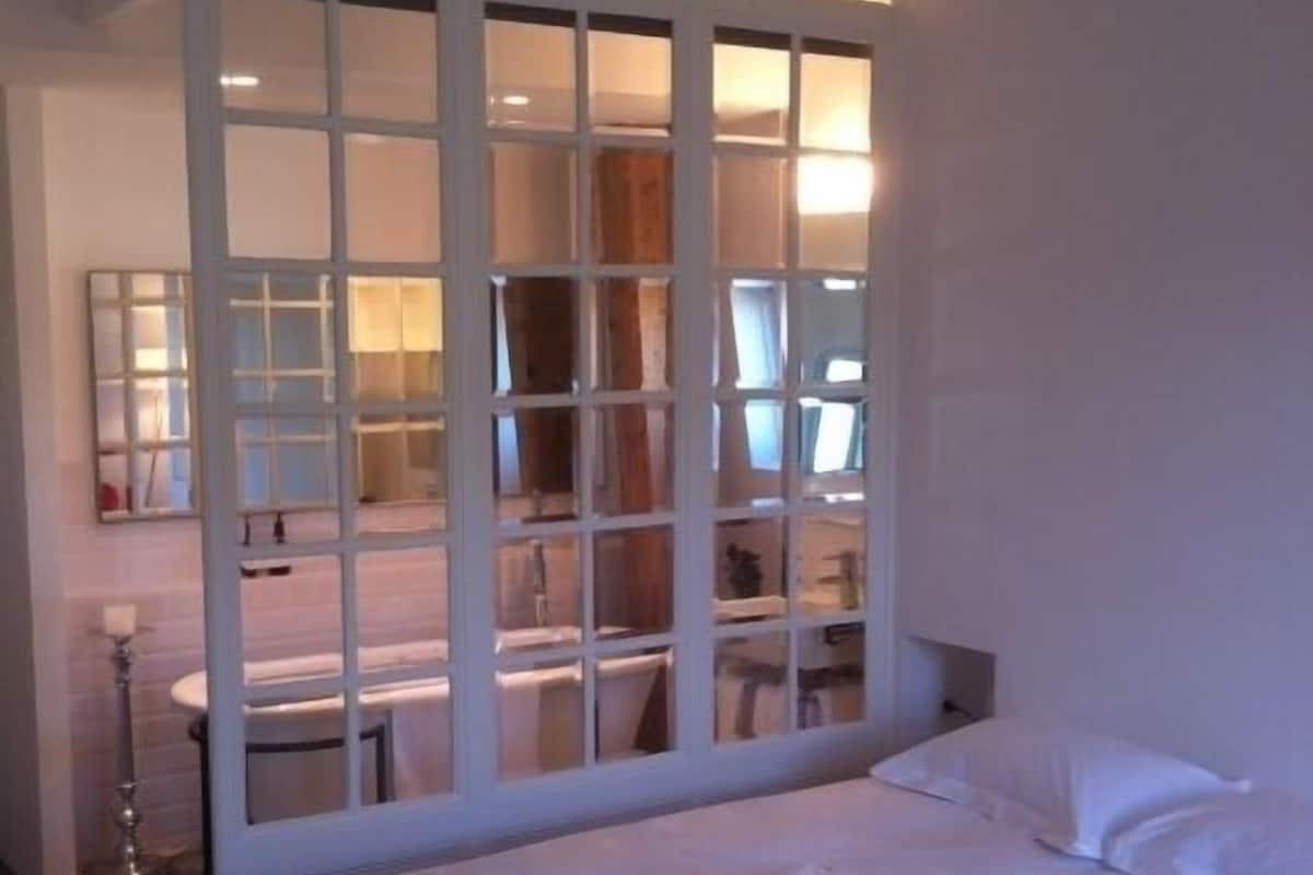 Una habitación de hotel con una cama grande, un escritorio con silla y un espejo.