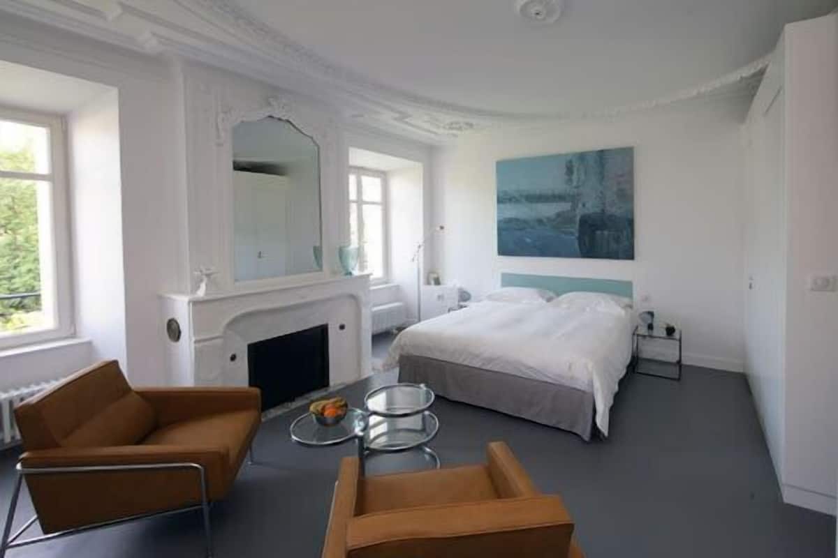 Un dormitorio moderno con una cama grande, una chimenea, un sofá y una mesa de comedor.