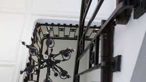 A corner of a room with a white ceiling and a black metal railing. - L'Hôtel Particulier (Nancy)