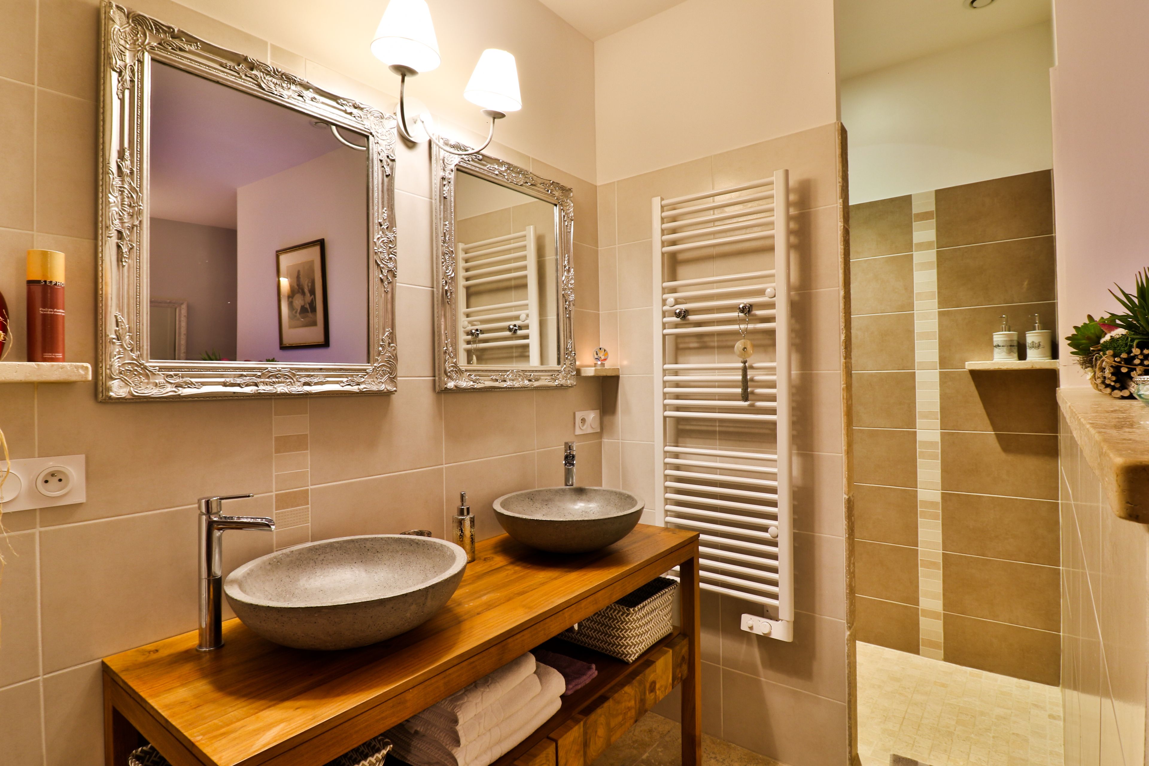 A bathroom with a wooden vanity, a large mirror, and a built-in towel warmer.