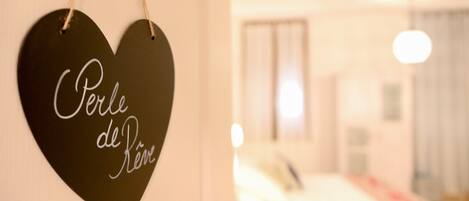 A heart-shaped sign with the text "Perle de Réve" hanging on a wall.