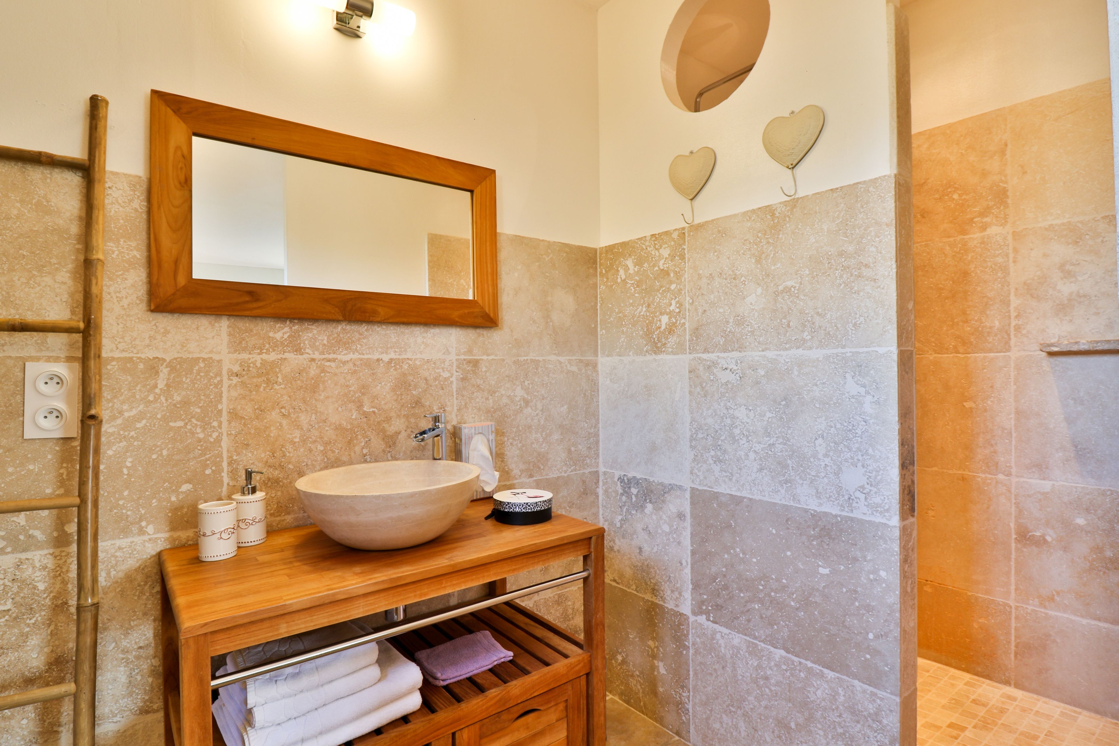 Un bagno con un mobile bagno in legno, uno specchio grande, un lavandino e una zona doccia.