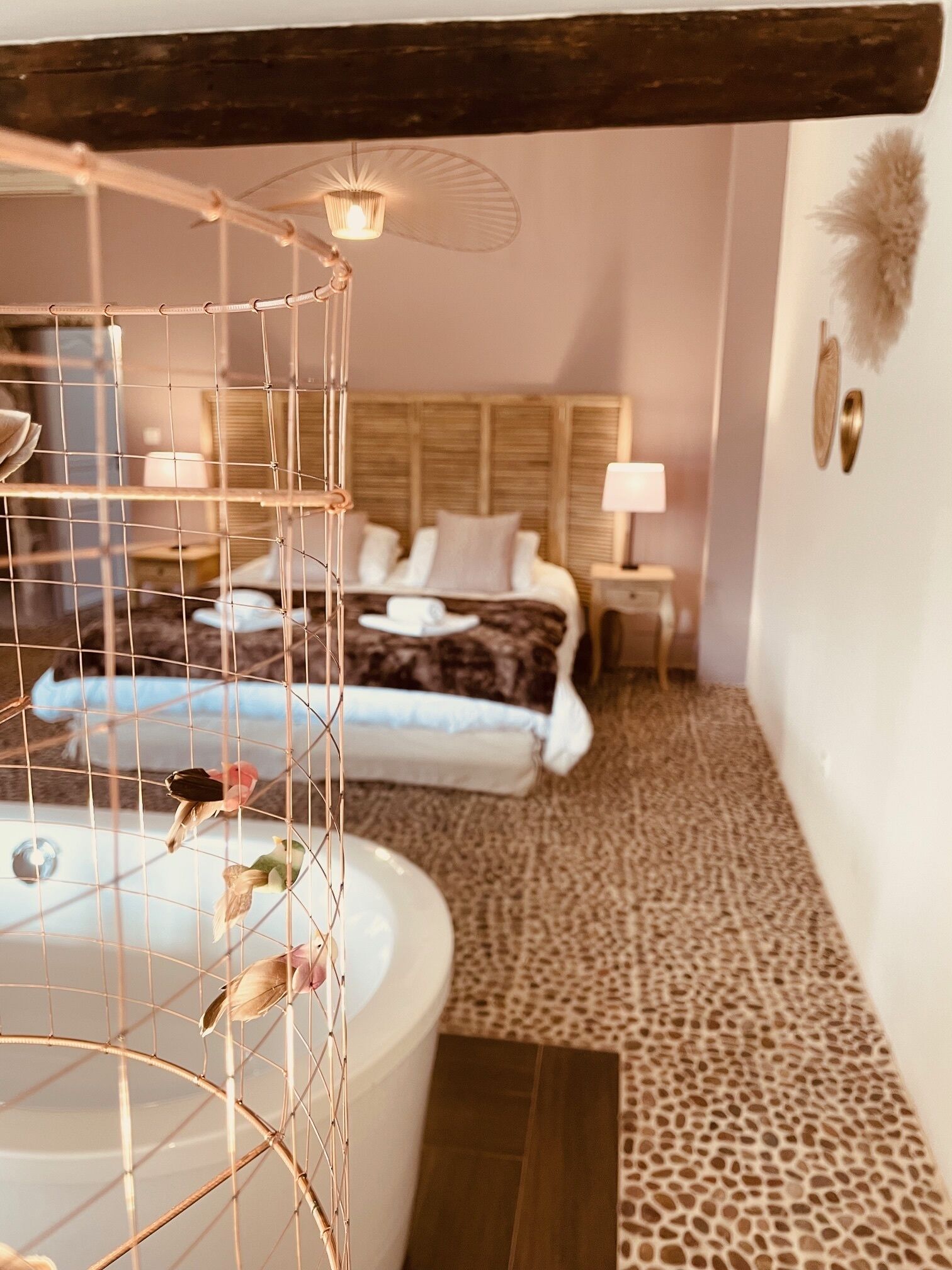 Een slaapkamer met een bed, nachtkastjes, een lamp en een decoratief wandobject.