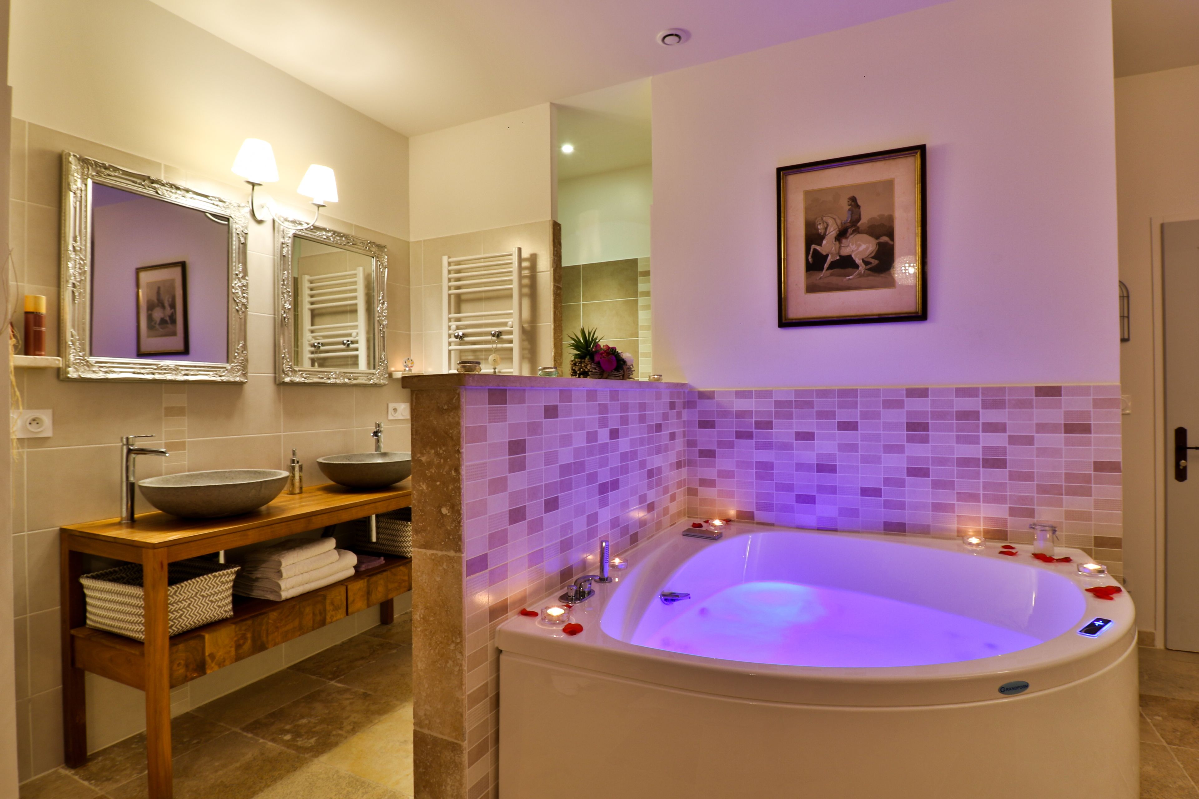 A modern bathroom with a large bathtub, two sinks, and a vanity with storage.