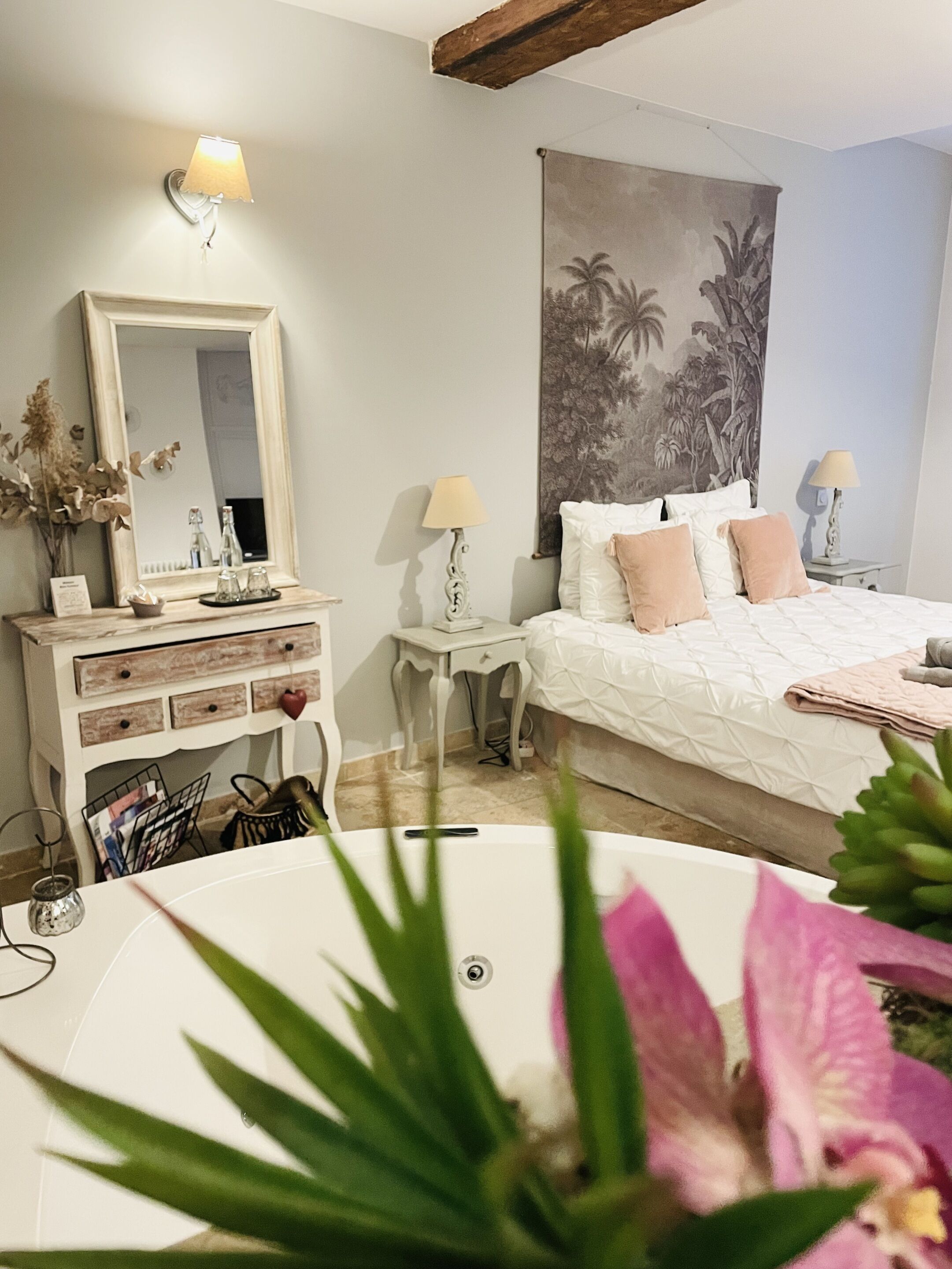 A bedroom with a large bed, a dresser, a mirror, and a painting on the wall.