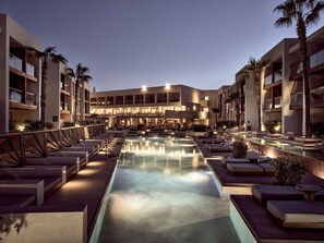 Un hôtel doté d’une piscine, d’un espace extérieur aménagé et de palmiers.