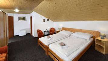 A room with two wooden beds, a small desk, a chair, and a lamp.