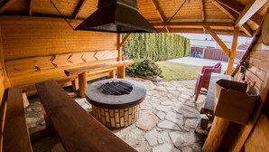 A wooden cabin with a stone patio, a fire pit, and outdoor seating.