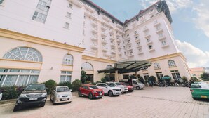 A multi-story hotel with a large parking area and a covered entrance. - Saigon Dalat Hotel (Xuan Huong - Da Lat)