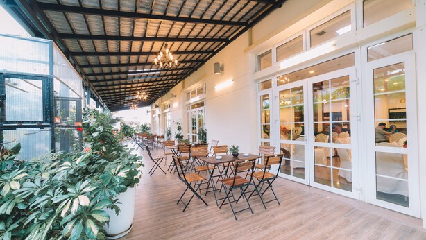 An indoor dining area with wooden tables and chairs, potted plants, and large windows. - Saigon Dalat Hotel (Xuan Huong - Da Lat)