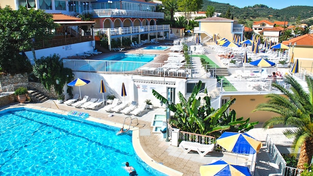Un resort con una amplia piscina, tumbonas, sombrillas y vistas del paisaje circundante.