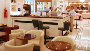 Un hall de hotel con zona de bar, distribución de asientos y una araña.