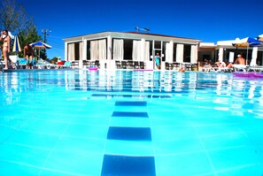 A swimming pool with lounge chairs and umbrellas.