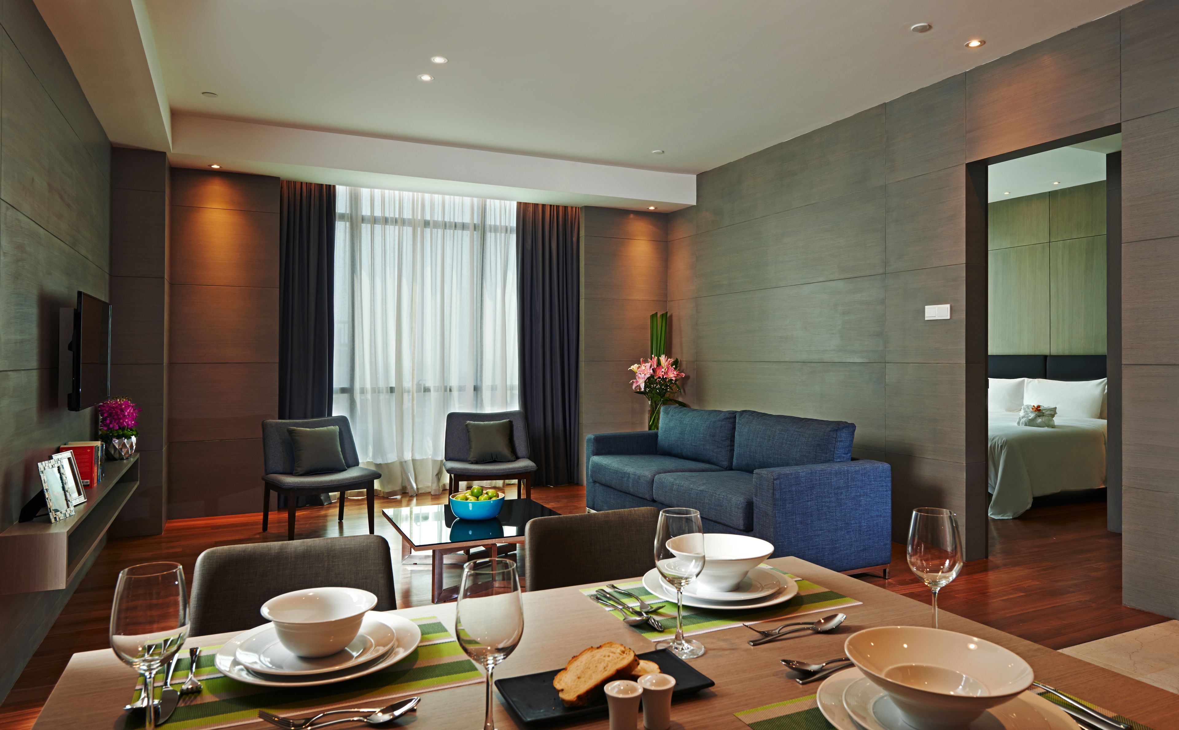 Una habitación de hotel moderna con comedor, sofá y cama.