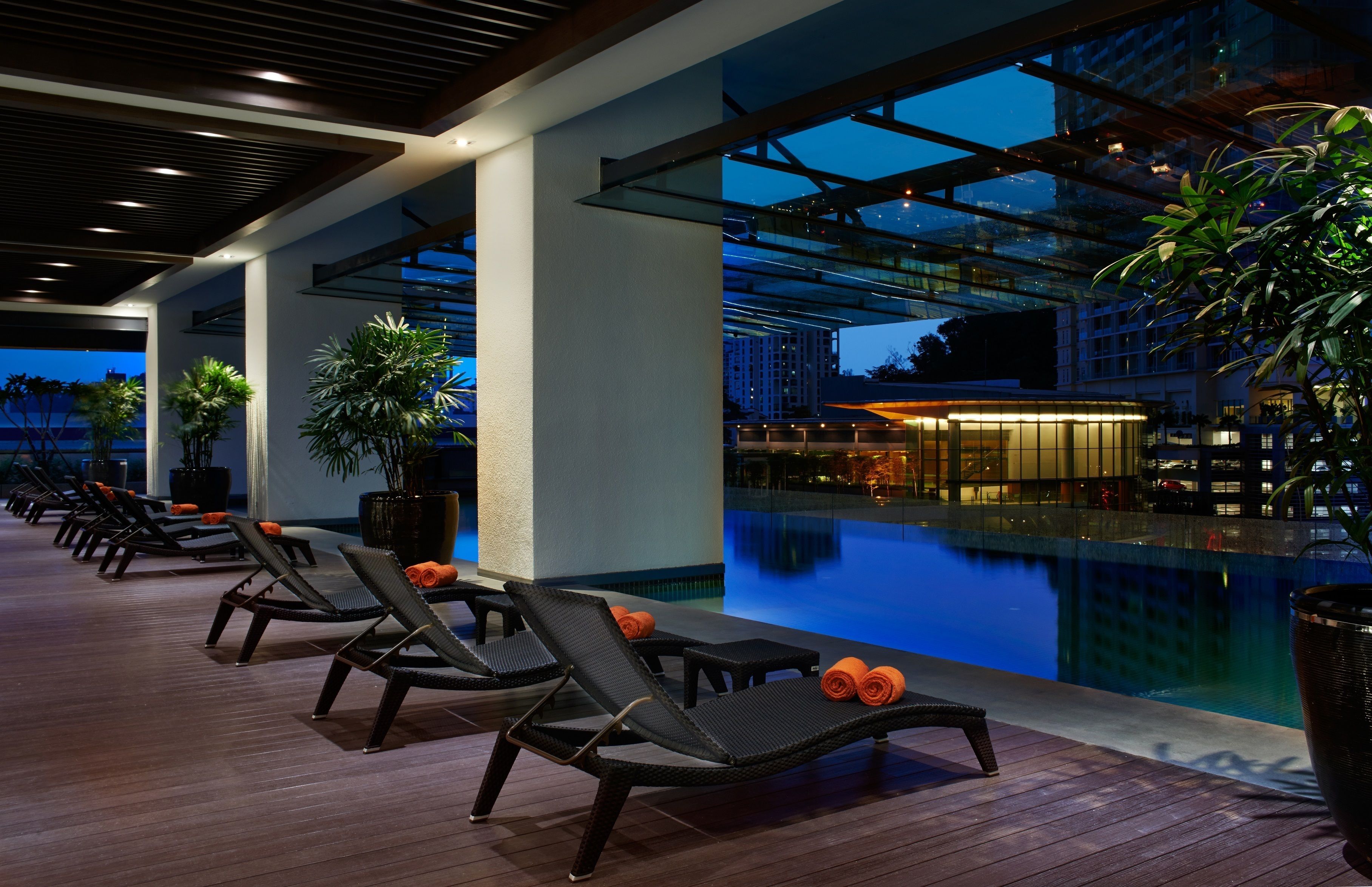 Un espace piscine moderne, avec des chaises longues et une piscine entourée de parois en verre.