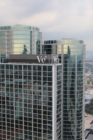 A modern high-rise building with reflective glass windows and a prominent 'Ve' logo. - V E Hotel & Residence (Kuala Lumpur)
