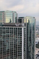 A modern high-rise building with reflective glass windows and a prominent 'Ve' logo.