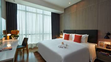 Een moderne hotelkamer met een groot bed, een bureau en een stoel. Er is een raam met gordijnen, een nachtkastje met een lamp, en een klein tafeltje met een bloemenvaas.